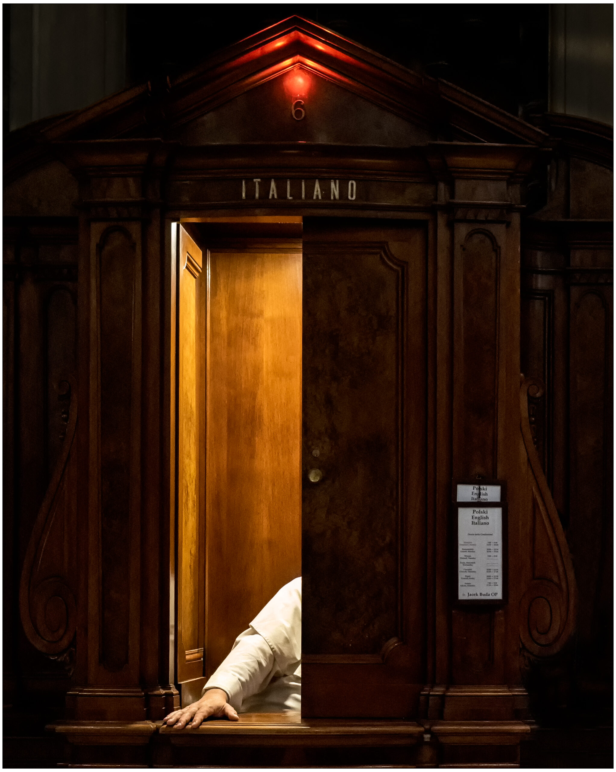 Cabine de confession en bois avec porte entrouverte et bras appuyé, langue italienne indiquée.