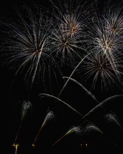 Feux d’artifice en étoiles dans le ciel nocturne Feux d'artifice lumineux éclatant dans le ciel nocturne avec traînées scintillantes sur fond noir.