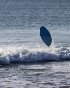 Planche de surf lancée par une vague éclaboussante Planche de surf projetée en l'air par une vague éclaboussante dans l'océan.