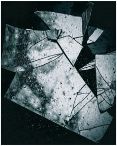 Fragments de miroir cassé avec des gouttes d'eau posés sur une surface sombre. #explos thèmes photo club