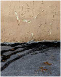 Mur beige avec peinture écaillée au-dessus d’un sol goudronné noir taché. #explos thèmes photo club