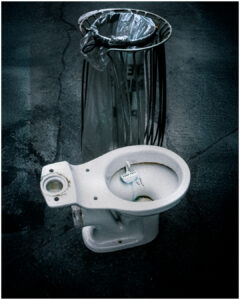 Siège de toilette en céramique usé posé sur sol béton près d'une corbeille métallique. #explos thèmes photo club