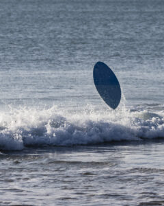 Planche de surf en plein saut au-dessus d'une vague près du rivage dans l'océan.